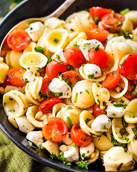 Caprese pasta salad made with tomatoes, marinated fresh mozzarella cheese, fresh basil, and a mouthwatering homemade Italian herb vinaigrette! #pastasalad #caprese #tomatobasil #italian #sidedish #potluck #bbq #summer