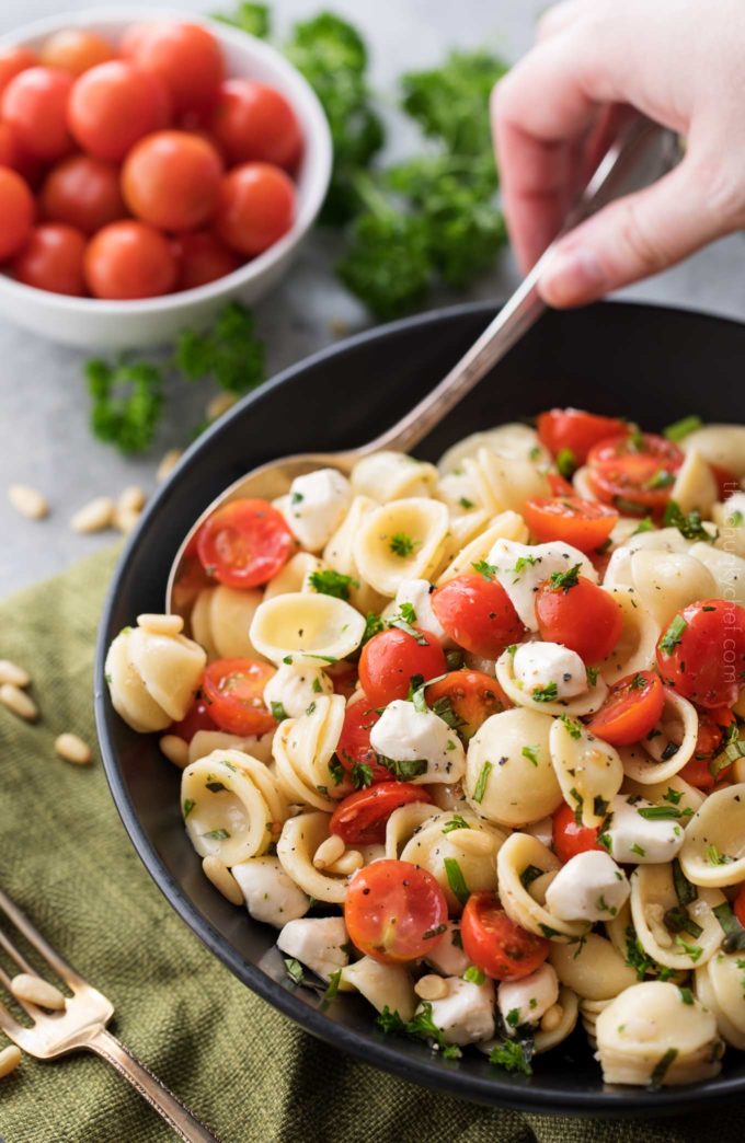 Serving spoonful of caprese pasta salad