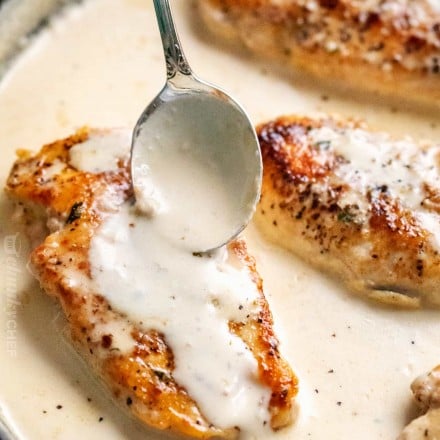 Chicken breasts in pan with spoonful of garlic sauce on top