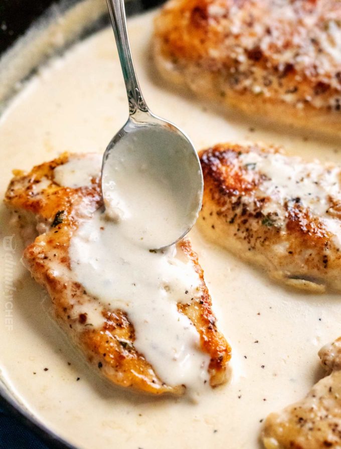 Chicken breasts in pan with spoonful of garlic sauce on top