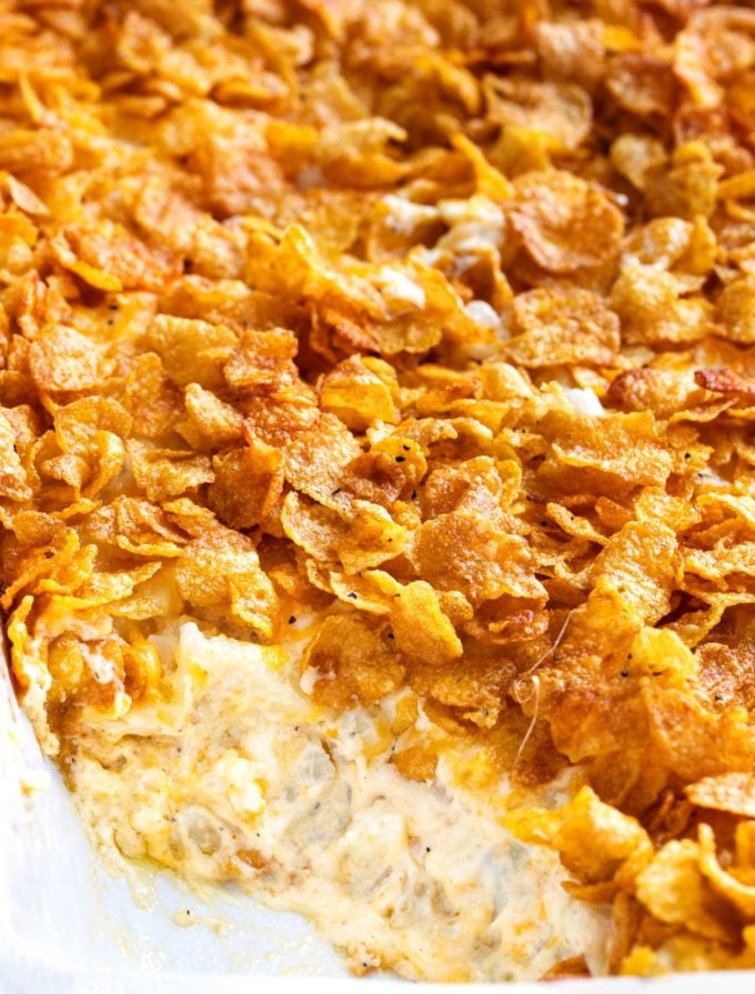 Funeral potatoes in white baking dish with scoop out