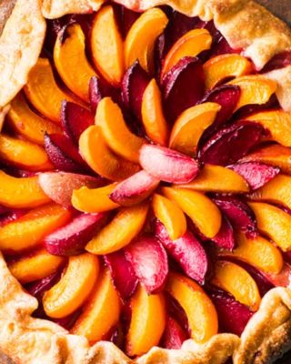 Every bit as mouthwatering as fruit pie, this stone fruit galette is a fuss-free way to enjoy the freshest seasonal fruits! Tender pie crust envelopes a mixture of plums, apricots and sugar, and is perfect topped with a scoop of frosty vanilla ice cream! #pie #galette #dessert #easyrecipe #fruit #plum #piecrust