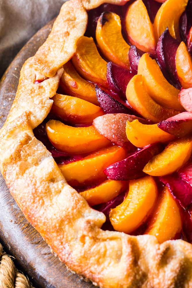 Every bit as mouthwatering as fruit pie, this stone fruit galette is a fuss-free way to enjoy the freshest seasonal fruits!  Tender pie crust envelopes a mixture of plums, apricots and sugar, and is perfect topped with a scoop of frosty vanilla ice cream! #pie #galette #dessert #easyrecipe #fruit #plum #piecrust