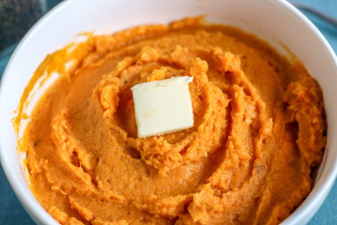 Mashed sweet potatoes in bowl with butter