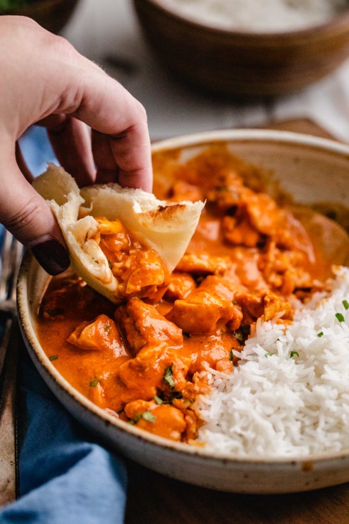 Scooping chicken tikka masala with naan bread