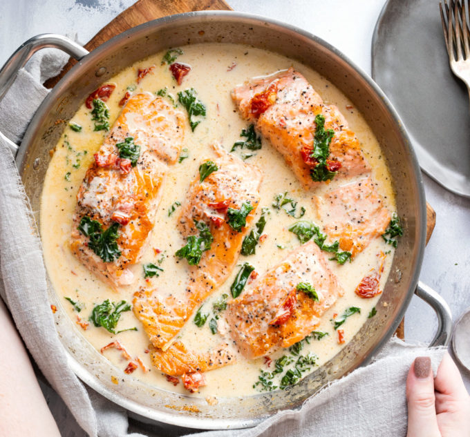 Salmon filets in creamy tuscan sauce in skillet