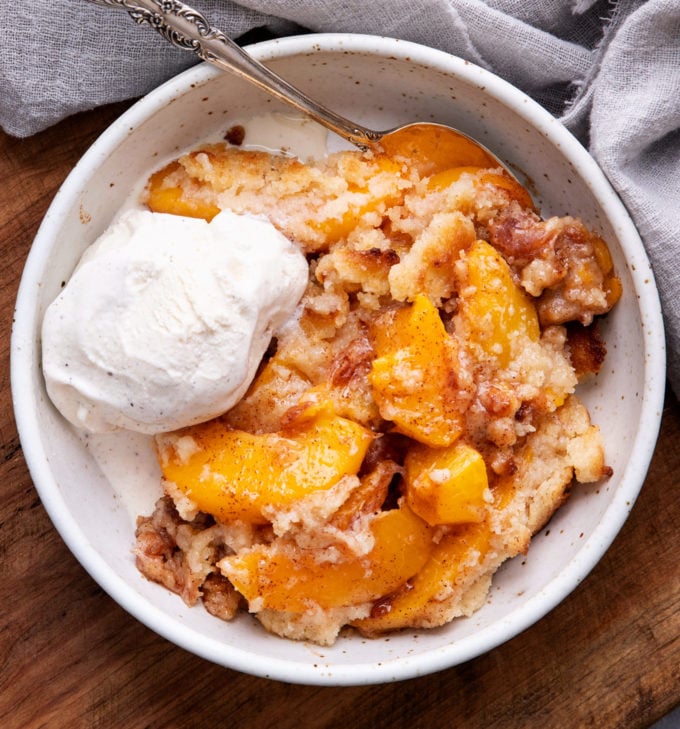 View of cobbler in white bowl with vanilla ice cream