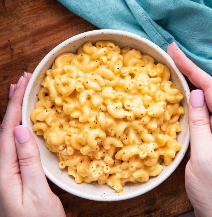 Holding a while bowl of macaroni