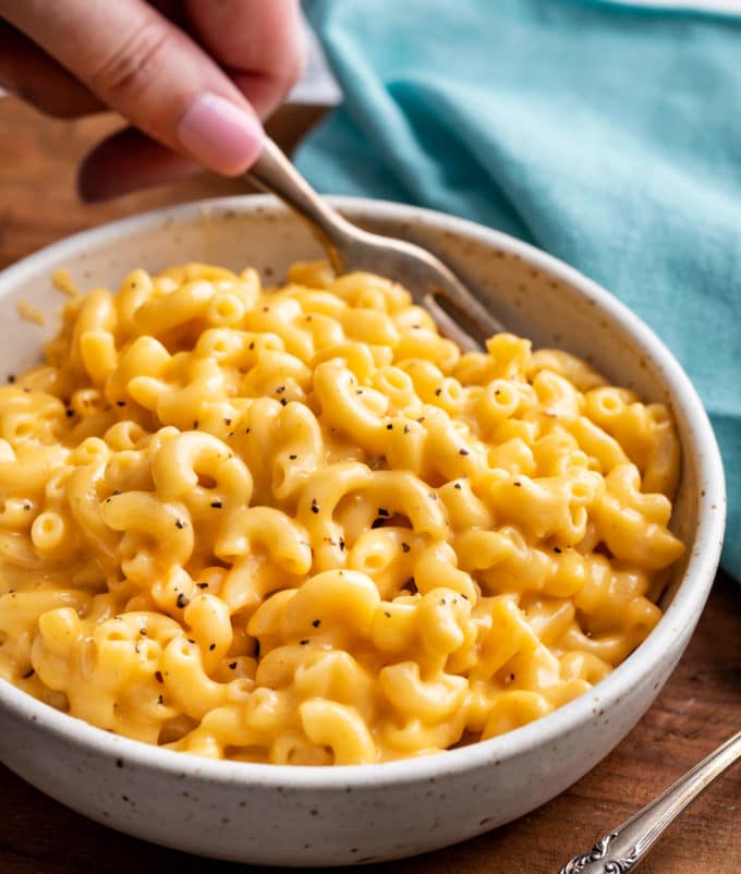 Holding fork in bowl of mac and cheese