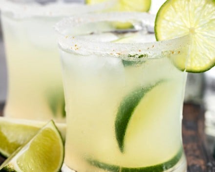 Fresh margaritas with lime wedges and salt rims