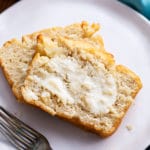 Two slices of beer bread with butter on white plate
