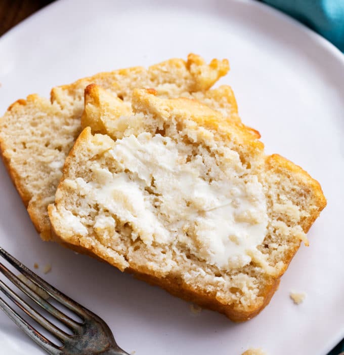 Two slices of beer bread with butter on white plate