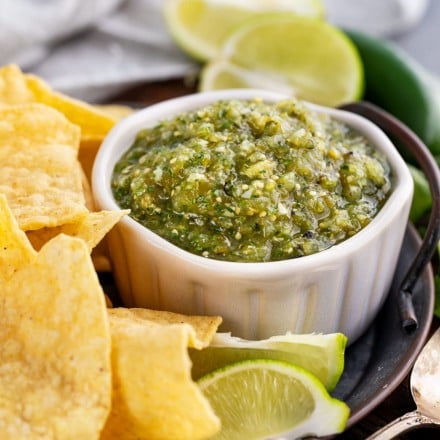 roasted tomatillo salsa in white bowl with chips around it