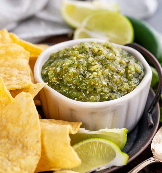 roasted tomatillo salsa in white bowl with chips around it