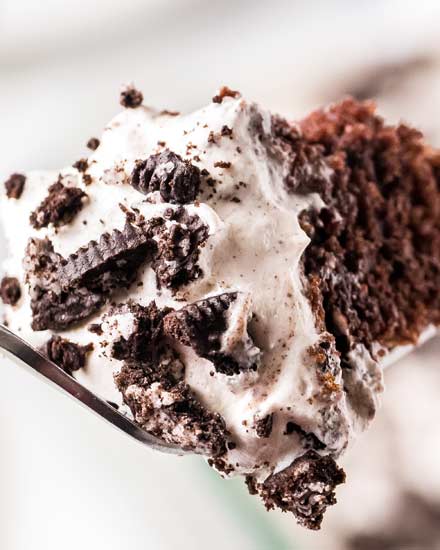 Rich chocolate cake with drizzles of cookies and cream pudding, topped with fluffy whipped cream and chopped Oreo cookies! This party favorite recipe is a natural make ahead dessert recipe. #pokecake #chocolatecake #oreo #pudding #dessert #baking #easydessert