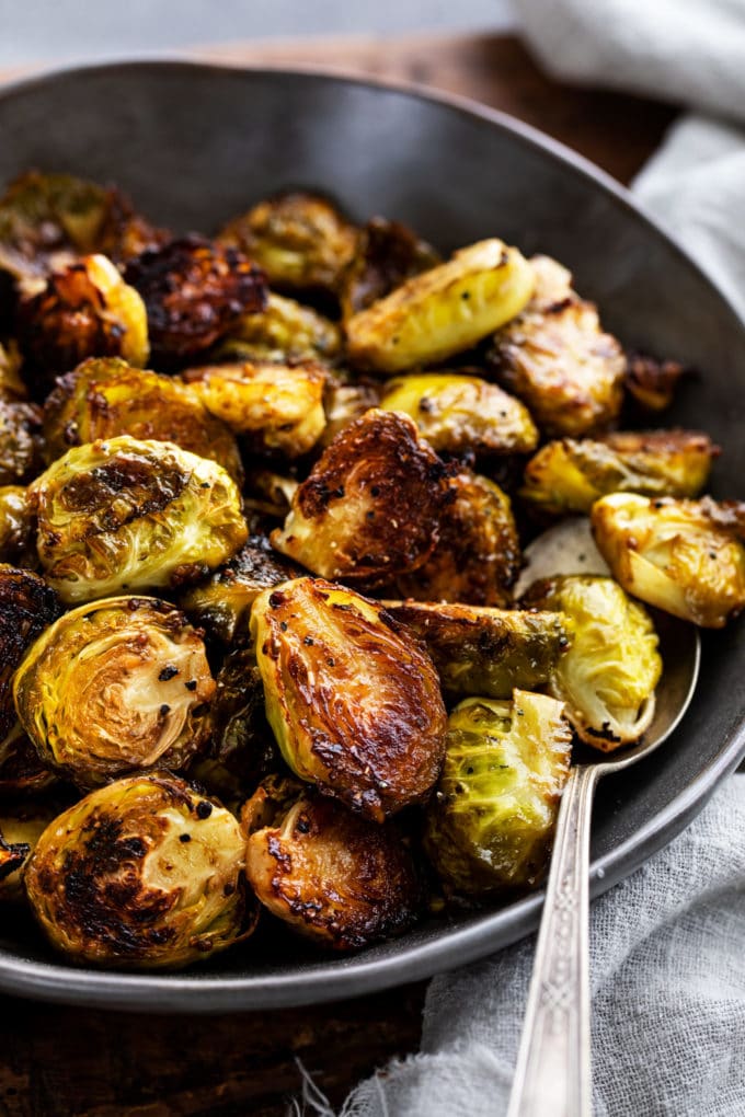 black bowl of roasted brussels sprouts with spoon