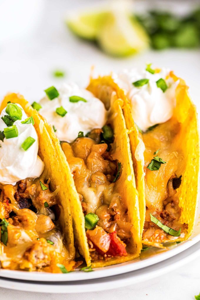 closeup view of chicken tacos on plate with sour cream and green onions