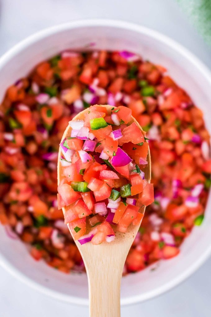 scoop of pico de gallo on wooden spoon