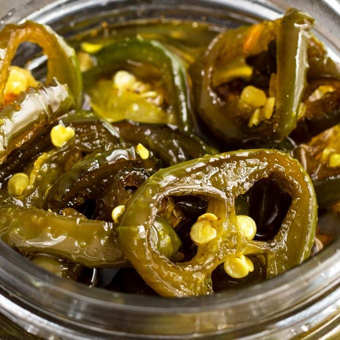 close up of candied jalapenos in glass jar