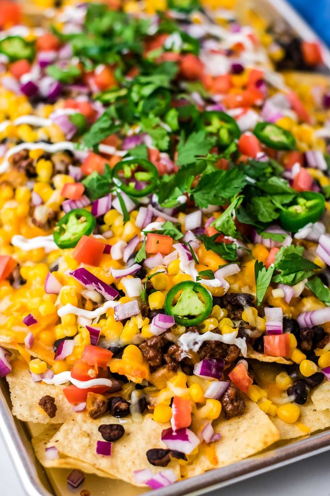 These Sheet Pan Nachos are completely loaded with beef, black beans, cheese, onions, and all the toppings you could want! So easy to make in just 20 minutes and are perfect for any party! #nachos #beef #loaded #mexican #easyrecipe #sheetpan #appetizer #partyfood 