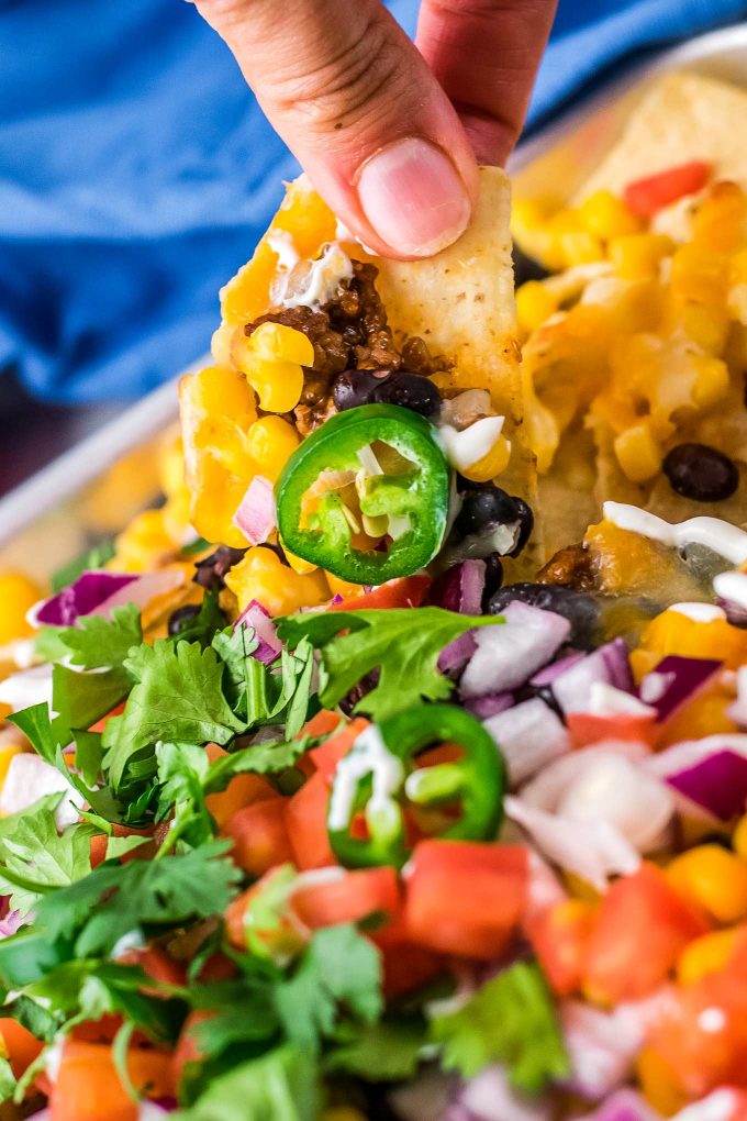 holding a loaded nacho from the sheet pan