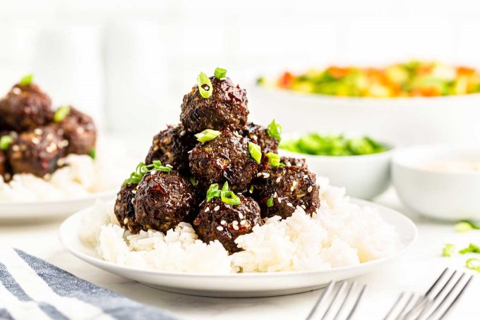 stack of thai meatballs over rice on white plate