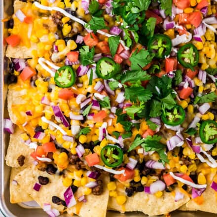 sheet pan beef nachos piled with all the toppings