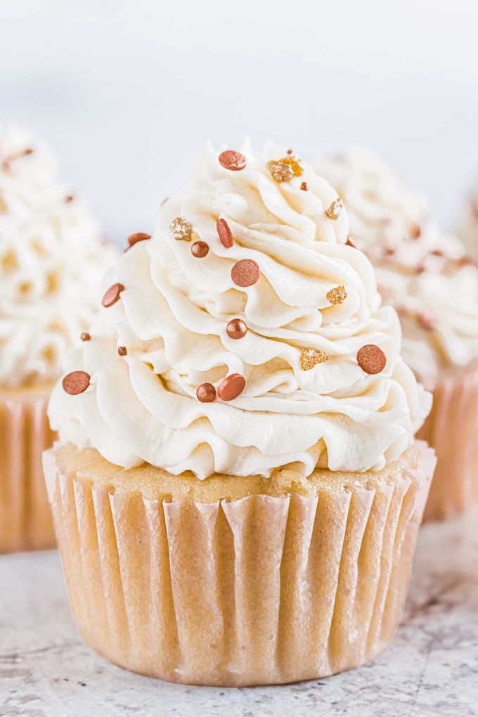 closeup photo of vanilla cupcake with swirled buttercream and sprinkles