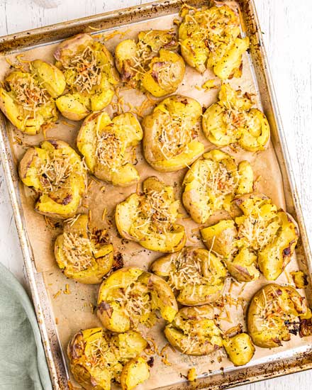 Crispy Smashed Potatoes are so fluffy on the inside, golden/crispy on the outside, and smothered in garlic and parmesan cheese!  The perfect family-pleasing side dish to serve with dinner. #potatoes #smashed #garlic #parmesan #sidedish #sidedishes #dinner