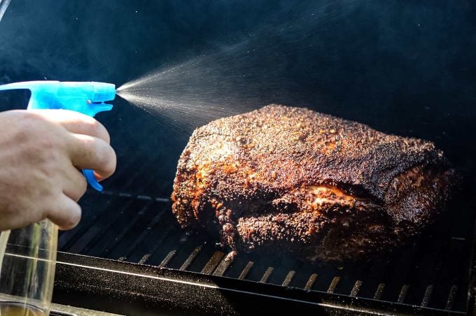 Spritzing pork shoulder while smoking