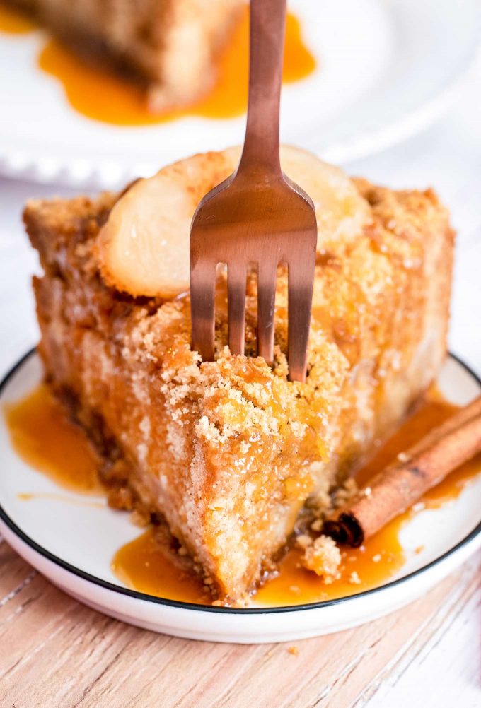 fork cutting into slice of cake with apples