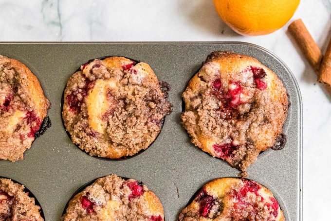 These Cranberry Orange Muffins are made with tart cranberries, bright orange zest, and sweet freshly squeezed orange juice folded gently into a thick and rich classic muffin batter. Perfect for the holidays, school mornings, or anytime! #muffins #cranberry #orange #breakfast #dessert #easyrecipe #baking