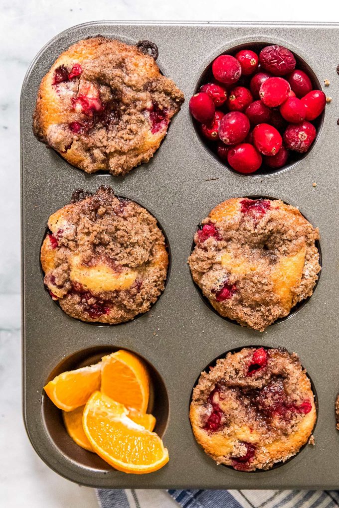 cranberry orange muffins in muffin pan with fresh fruit