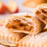 apple turnovers stacked on plate, one cut open