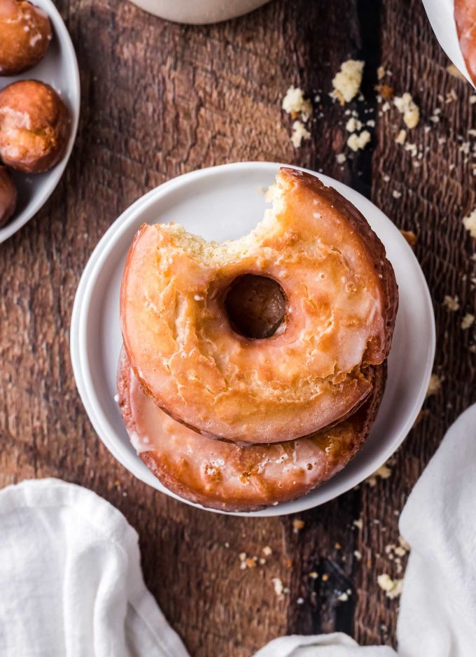 Two donuts with bite taken out of them on plate