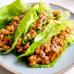 3 lettuce wraps filled with chicken on white plate