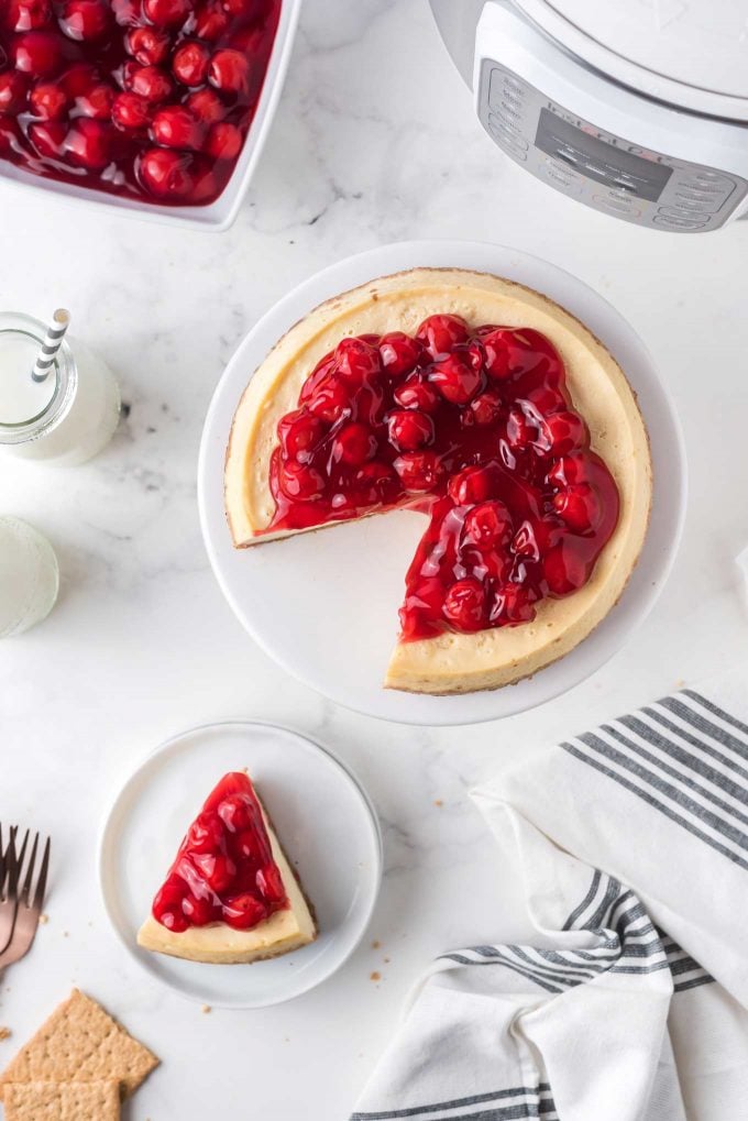 This easy Instant Pot Cheesecake is the perfect dessert recipe! Classic vanilla cheesecake comes out so creamy and rich, with a buttery graham cracker crust, and topped with classic cherry pie filling! #dessert #cheesecake #instantpot #pressurecooker #baking #easyrecipe #vanilla 