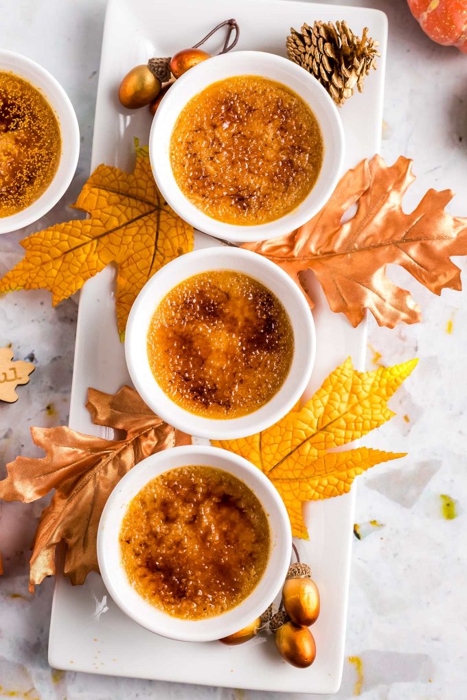 ramekins with creme brulee on platter surrounded by fall leaves