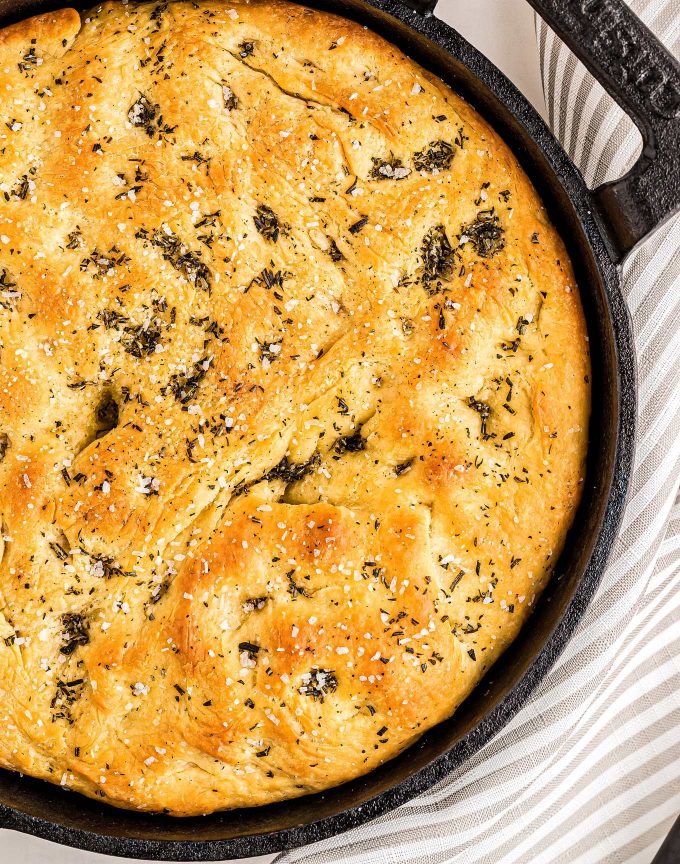 This easy focaccia recipe has a crispy crust, chewy middle, and plenty of herbs and salt in each bite!  With the option to let the dough rest for just a few hours, or overnight, this bread recipe is perfect for any dinner or party! #bread #focaccia #rosemary #seasalt #baking #yeast #baked #artisan #homemade