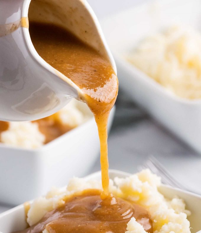 pouring homemade gravy over mashed potatoes