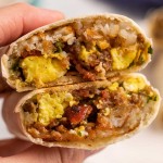 holding a halved breakfast burrito