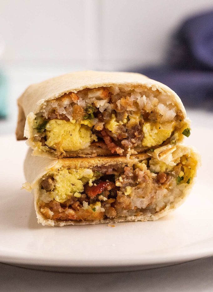 These breakfast burritos are packed with eggs, bacon, sausage, cheese and tater tots and will give you the protein punch you need to get your day started off right!  Easy to prep ahead and freeze, giving you amazing on-the-go burritos all week long! #breakfast #burritos #eggs #bacon #sausage #cheese #hashbrowns #tatertots #freezerfriendly #mealprep