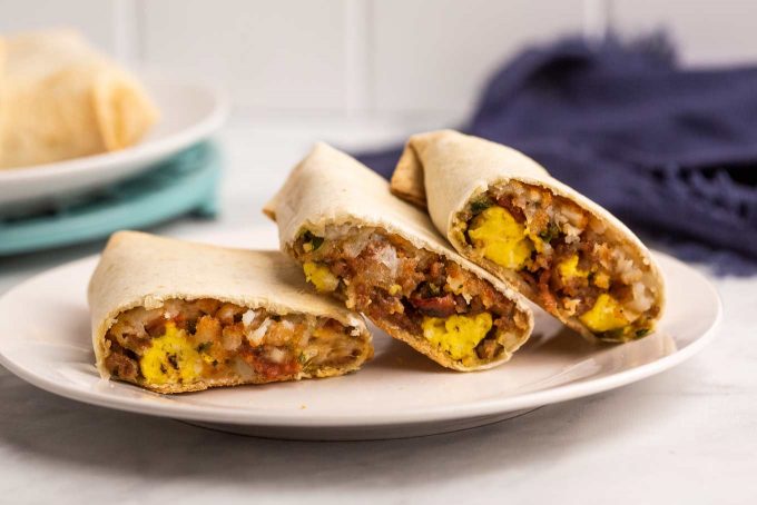 These breakfast burritos are packed with eggs, bacon, sausage, cheese and tater tots and will give you the protein punch you need to get your day started off right!  Easy to prep ahead and freeze, giving you amazing on-the-go burritos all week long! #breakfast #burritos #eggs #bacon #sausage #cheese #hashbrowns #tatertots #freezerfriendly #mealprep