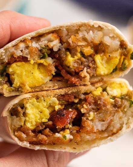 These breakfast burritos are packed with eggs, bacon, sausage, cheese and tater tots and will give you the protein punch you need to get your day started off right!  Easy to prep ahead and freeze, giving you amazing on-the-go burritos all week long! #breakfast #burritos #eggs #bacon #sausage #cheese #hashbrowns #tatertots #freezerfriendly #mealprep