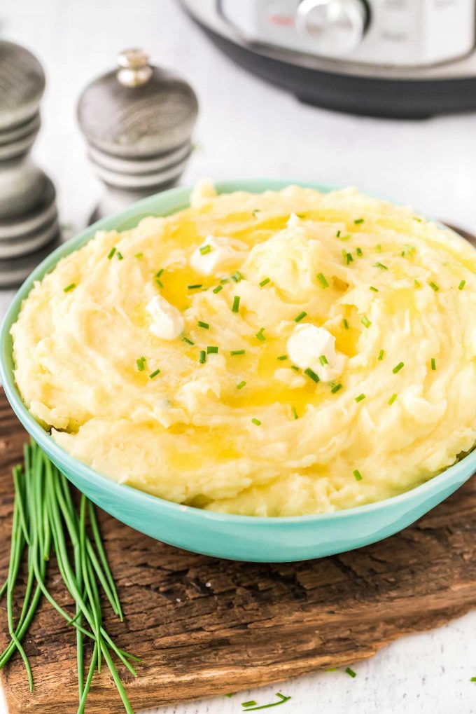 bowl of potatoes with butter and chives on cutting board