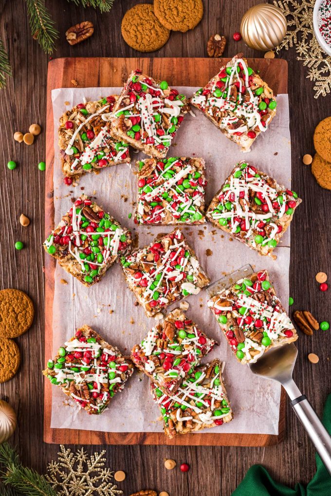 scattered 7 layer bars on holiday cutting board with a spatula