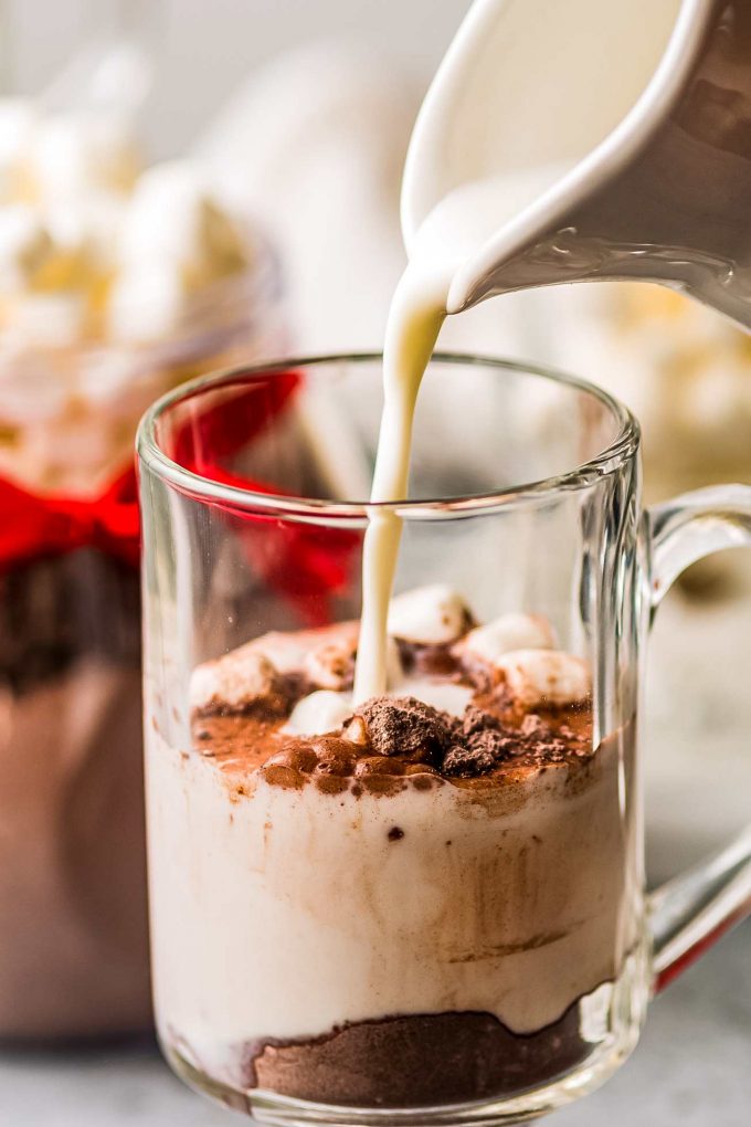 pouring milk into mug with hot cocoa mix