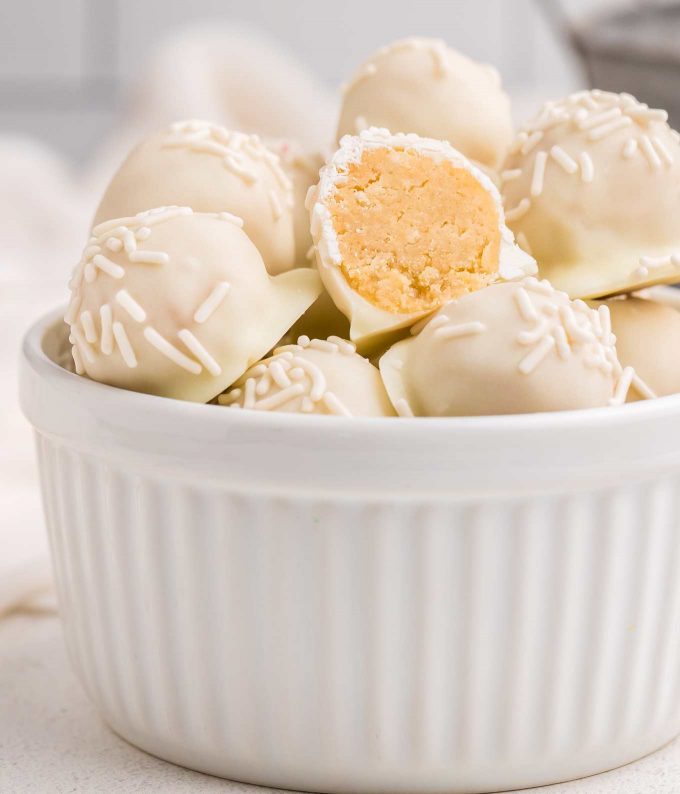 white chocolate sugar cookie truffles in bowl with one cut in half