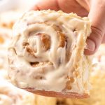 holding a cinnamon roll with icing