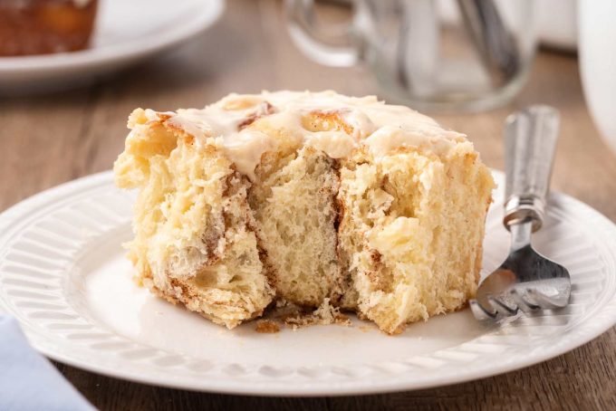 cinnamon roll on plate with bite taken out of it